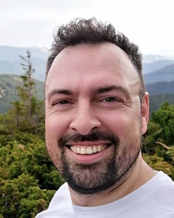 Mykola Vorobiov, photographed outdoors against forested mountains.